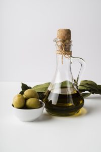 Botella de aceite de oliva virgen extra con aceitunas verdes